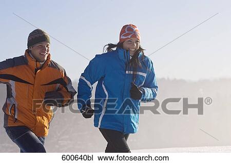 Stock Image - young couple jogging through winter landscape. Fotosearch