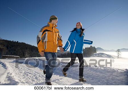 Stock Image - young couple running hand in hand through winter landscape. Fotosearch