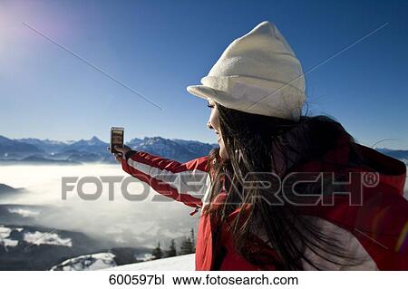 young woman in the mountains taking picture with camera phone View Large Photo Image Stock Image - young woman in the mountains taking picture with camera phone. Fotosearch