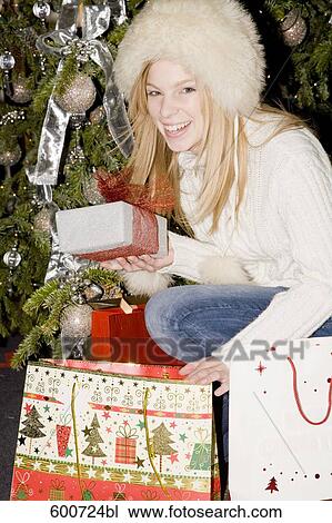 Stock Image - young woman looking through her bag with christmas shoppings. Fotosearch