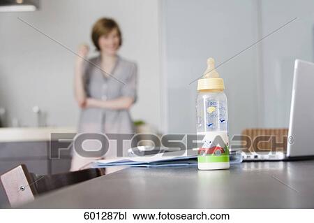 baby bottle and computer on table with woman standing in background View Large Photo Image Stock Image - baby bottle and computer on table with woman standing in background. Fotosearch