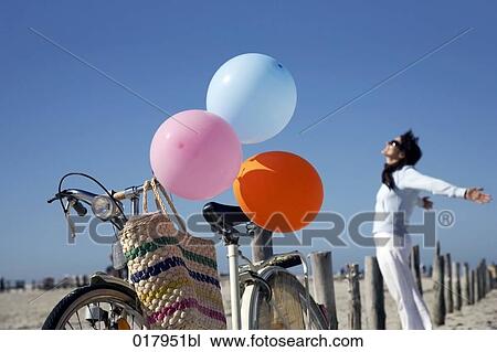 bicycle with colourful balloons on beach and happy woman in background View Large Photo Image Stock Image - bicycle with colourful balloons on beach and happy woman in background. Fotosearch
