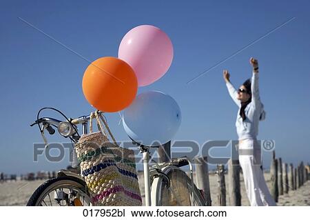 bicycle with colourful balloons on beach and happy woman in background View Large Photo Image Stock Image - bicycle with colourful balloons on beach and happy woman in background. Fotosearch