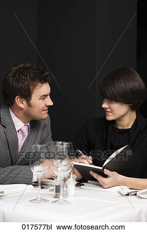 Stock Image - businessman and female colleague having business lunch. Fotosearch
