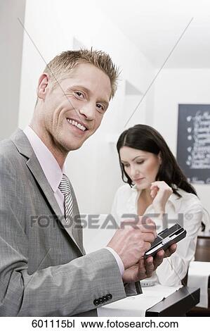 businessman at restaurant working with smartphone female colleague in background View Large Photo Image Stock Image - businessman at restaurant working with smartphone female colleague in background. Fotosearch