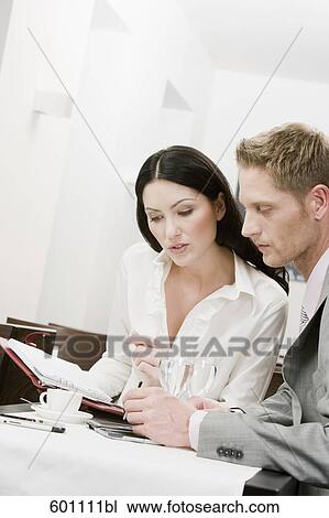 businesswoman and male colleague at restaurant reading document View Large Photo Image Stock Image - businesswoman and male colleague at restaurant reading document. Fotosearch