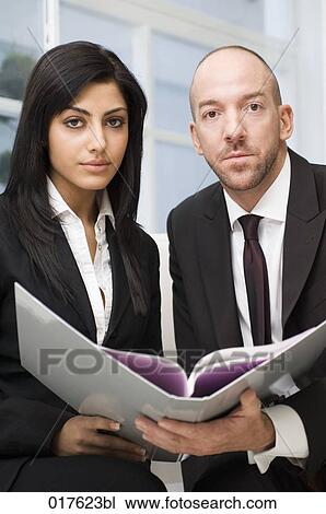 businesswoman and male colleague sitting together reading document View Large Photo Image Stock Image - businesswoman and male colleague sitting together reading document. Fotosearch