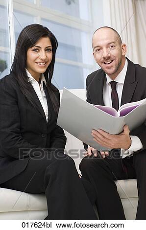 businesswoman and male colleague sitting together reading document View Large Photo Image Stock Image - businesswoman and male colleague sitting together reading document. Fotosearch