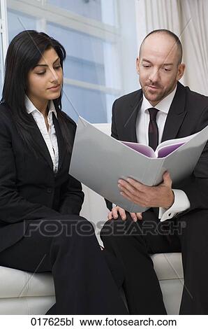 businesswoman and male colleague sitting together reading document View Large Photo Image Stock Image - businesswoman and male colleague sitting together reading document. Fotosearch