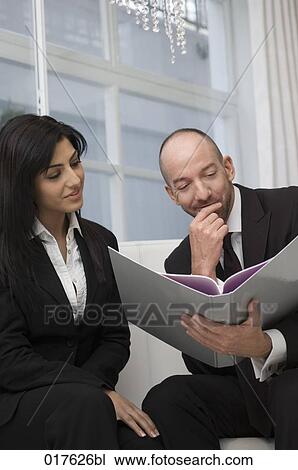 businesswoman and male colleague sitting together reading document View Large Photo Image Stock Image - businesswoman and male colleague sitting together reading document. Fotosearch