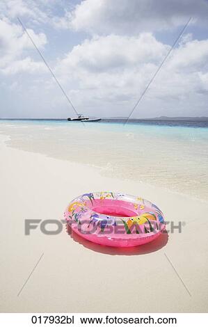 Stock Image - floating tyre on sandy beach. Fotosearch