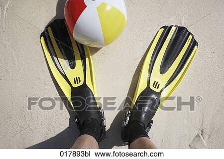 Stock Image - high angle view of man standing on beach wearing fins. Fotosearch