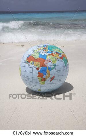 Stock Image - inflatable globe lying on sandy beach. Fotosearch