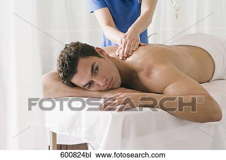 Stock Image - man lying on massage bench undergoing massage treatment. Fotosearch