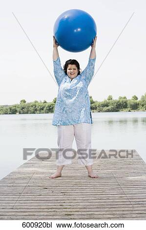 overweight woman doing exercises with blue ball on pier by lake View Large Photo Image Stock Image - overweight woman doing exercises with blue ball on pier by lake. Fotosearch