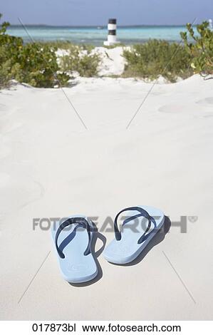 Stock Image - pair of flip flops on sandy beach. Fotosearch