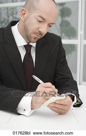 Stock Image - portrait of businessman writing note on post-it. Fotosearch