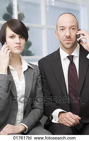 Stock Image - portrait of businesswoman and male colleague with mobile phones. Fotosearch