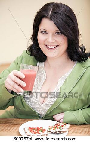 portrait of overweight woman sitting at table holding glass of juice View Large Photo Image Stock Image - portrait of overweight woman sitting at table holding glass of juice. Fotosearch
