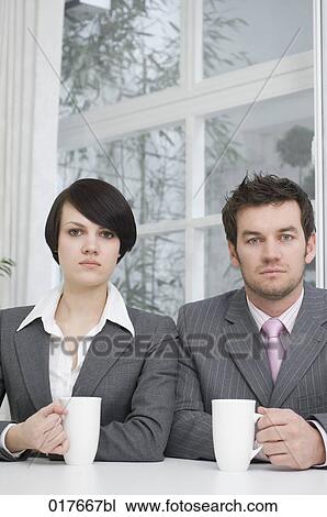 Stock Image - portrait of two business people sitting at table with cups. Fotosearch