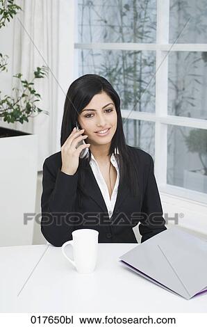 portrait of young businesswoman at desk talking on mobile phone View Large Photo Image Stock Image - portrait of young businesswoman at desk talking on mobile phone. Fotosearch