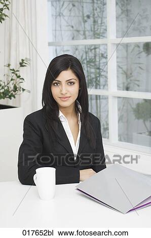 portrait of young businesswoman sitting at desk View Large Photo Image Stock Image - portrait of young businesswoman sitting at desk. Fotosearch