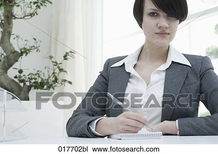 portrait of young businesswoman sitting at desk taking notes View Large Photo Image Stock Image - portrait of young businesswoman sitting at desk taking notes. Fotosearch