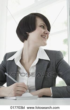 portrait of young businesswoman sitting at desk taking notes View Large Photo Image Stock Image - portrait of young businesswoman sitting at desk taking notes. Fotosearch