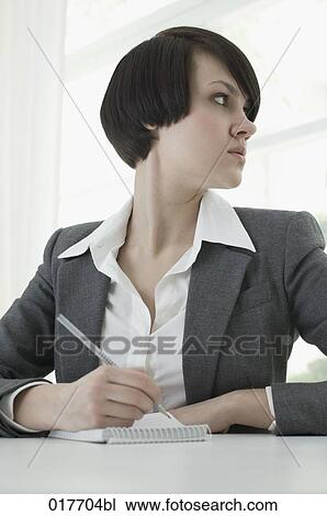 portrait of young businesswoman sitting at desk taking notes View Large Photo Image Stock Image - portrait of young businesswoman sitting at desk taking notes. Fotosearch