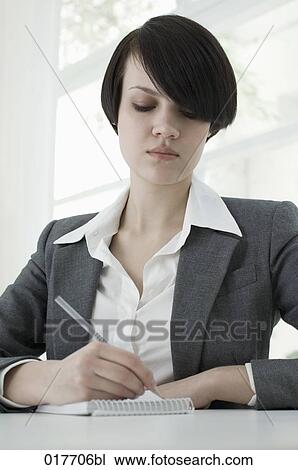portrait of young businesswoman sitting at desk taking notes View Large Photo Image Stock Image - portrait of young businesswoman sitting at desk taking notes. Fotosearch