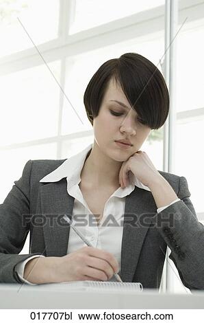 portrait of young businesswoman sitting at desk taking notes View Large Photo Image Stock Image - portrait of young businesswoman sitting at desk taking notes. Fotosearch