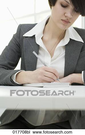 portrait of young businesswoman sitting at desk taking notes View Large Photo Image Stock Image - portrait of young businesswoman sitting at desk taking notes. Fotosearch