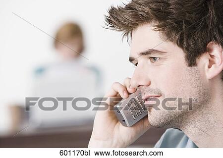 Stock Image - portrait of young man at home talking on the telephone. Fotosearch