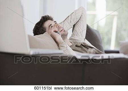 portrait of young man reclining on sofa and talking on mobile phone View Large Photo Image Stock Image - portrait of young man reclining on sofa and talking on mobile phone. Fotosearch