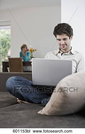 portrait of young man sitting on sofa with laptop computer View Large Photo Image Stock Image - portrait of young man sitting on sofa with laptop computer. Fotosearch