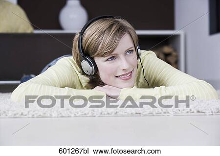 Stock Image - portrait of young woman at home listening to music with headphones. Fotosearch
