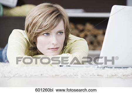 portrait of young woman lying on floor at home in front of laptop computer View Large Photo Image Stock Image - portrait of young woman lying on floor at home in front of laptop computer. Fotosearch