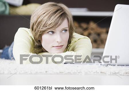 portrait of young woman lying on floor at home in front of laptop computer View Large Photo Image Stock Image - portrait of young woman lying on floor at home in front of laptop computer. Fotosearch