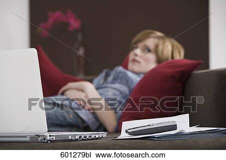 Stock Image - portrait of young woman relaxing on sofa. Fotosearch