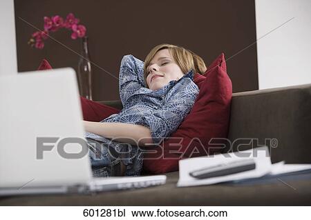 Stock Image - portrait of young woman relaxing on sofa. Fotosearch
