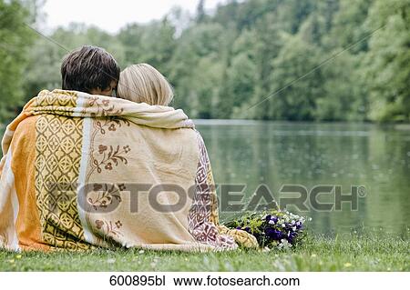 rear view of couple wrapped in blanket sitting at lake in park View Large Photo Image Stock Image - rear view of couple wrapped in blanket sitting at lake in park. Fotosearch