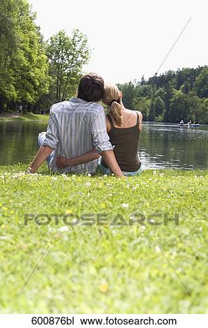 rear view of young couple sitting in park by lake View Large Photo Image Stock Image - rear view of young couple sitting in park by lake. Fotosearch