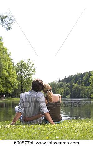 rear view of young couple sitting in park by lake View Large Photo Image Stock Image - rear view of young couple sitting in park by lake. Fotosearch