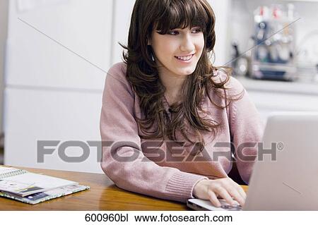 teenage girl sitting in kitchen and working with laptop computer View Large Photo Image Stock Image - teenage girl sitting in kitchen and working with laptop computer. Fotosearch