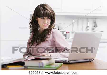 teenage girl sitting in kitchen doing homework in front of computer View Large Photo Image Stock Image - teenage girl sitting in kitchen doing homework in front of computer. Fotosearch