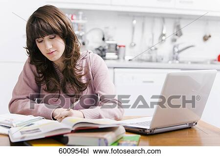 teenage girl sitting in kitchen doing homework in front of computer View Large Photo Image Stock Image - teenage girl sitting in kitchen doing homework in front of computer. Fotosearch