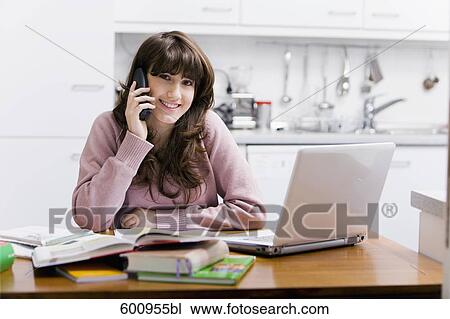 teenage girl sitting in kitchen in front of computer talking on telephone View Large Photo Image Stock Image - teenage girl sitting in kitchen in front of computer talking on telephone. Fotosearch