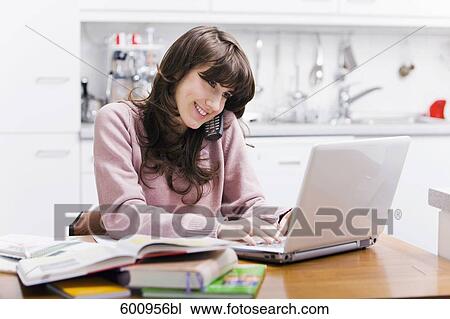 teenage girl sitting in kitchen in front of computer talking on telephone View Large Photo Image Stock Image - teenage girl sitting in kitchen in front of computer talking on telephone. Fotosearch