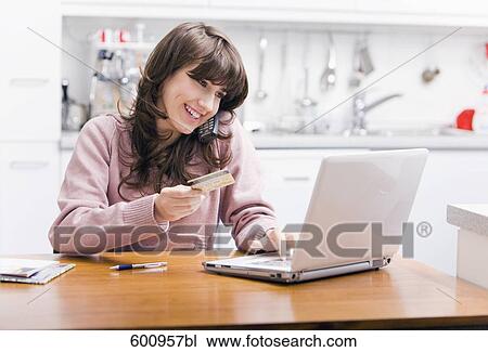 teenage girl sitting in kitchen in front of computer with credit card View Large Photo Image Stock Image - teenage girl sitting in kitchen in front of computer with credit card . Fotosearch