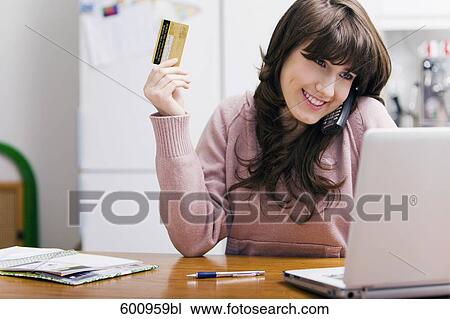 teenage girl sitting in kitchen in front of computer with credit card View Large Photo Image Stock Image - teenage girl sitting in kitchen in front of computer with credit card . Fotosearch